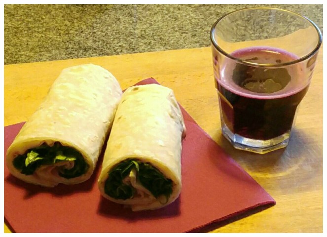 Piadina glutenfree di quinoa farcita con mortadella Bologna Igp, formaggio Brie e rucola. Accanto un bicchiere di vino Lambrusco