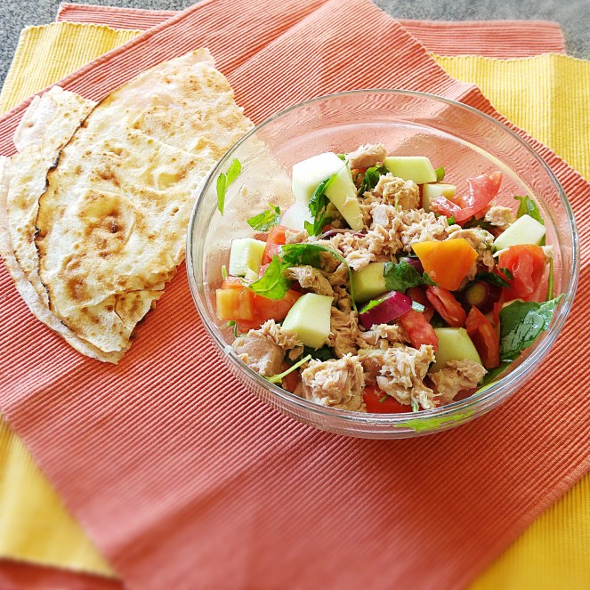 La nostra insalata di cetriolo carosello, pomodoro cuore di bue, cipollotti, tonno e rucola accompagnata da pane guttiau senza glutine.